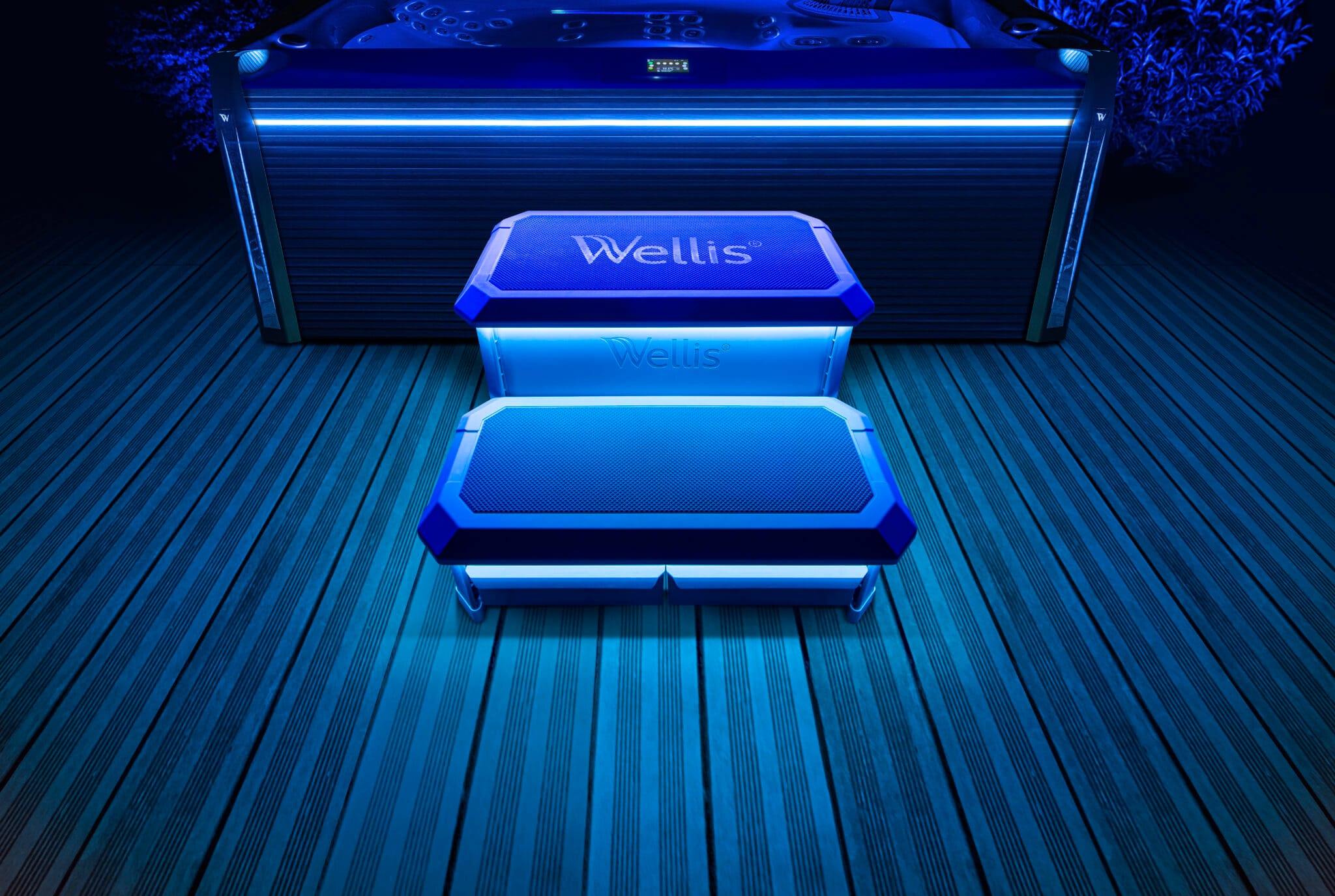 Escalier Wellis Smart-In Step éclairé par ses LED bleues devant un spa, de nuit